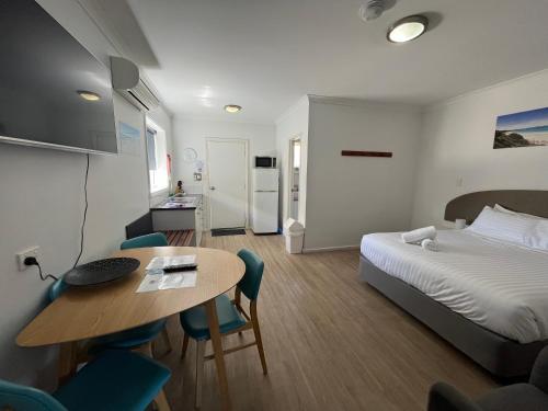 ein Hotelzimmer mit einem Bett, einem Tisch und Stühlen in der Unterkunft Clearwater Motel Apartments in Esperance