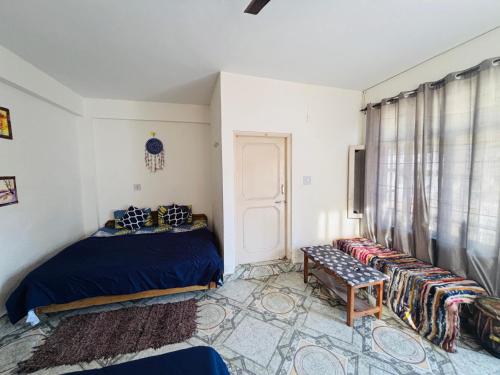 a bedroom with a bed and a bench and a window at Rahgir Mcleodganj in McLeod Ganj