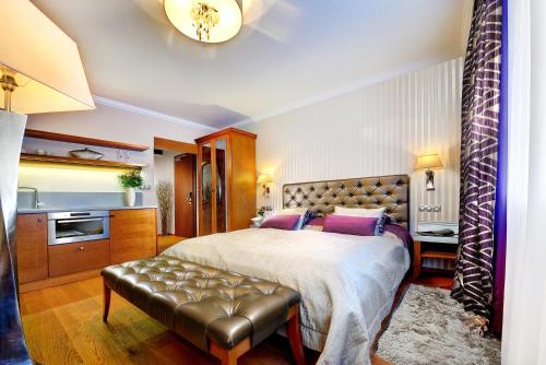 a bedroom with a large bed with a leather bench at Grand Hotel Praha in Tatranská Lomnica