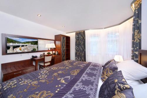a bedroom with a bed and a desk and a television at Hotel Central 1920 in Špindlerův Mlýn