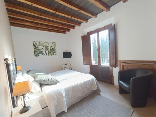 a white bedroom with a bed and a chair at Hotel La Perla Blanca in Ronda