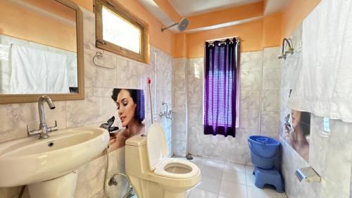 a woman is taking a picture of a bathroom at PineNest Cottages & Cafe in Jibhi