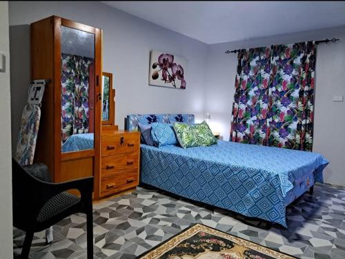 a bedroom with a bed and a dresser and a mirror at Tropical Almond Haven in Suva