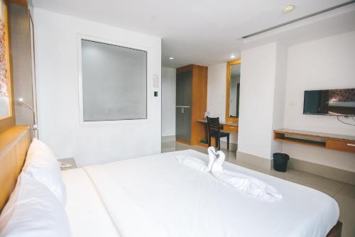 a bedroom with a white bed and a television at Jda Hotel in Ban Khlong Phruan