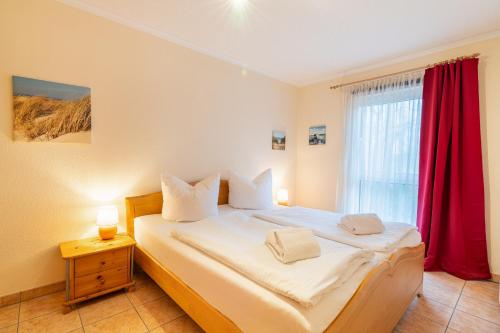a bedroom with a large bed with a red curtain at Düneneck 09 in Zempin