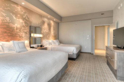 a hotel room with two beds and a flat screen tv at Courtyard by Marriott Pigeon Forge in Pigeon Forge