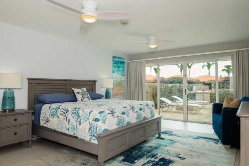 a bedroom with a bed and a view of a patio at Beachfront - Garden Delight 3BR condo - E125 in Palm-Eagle Beach