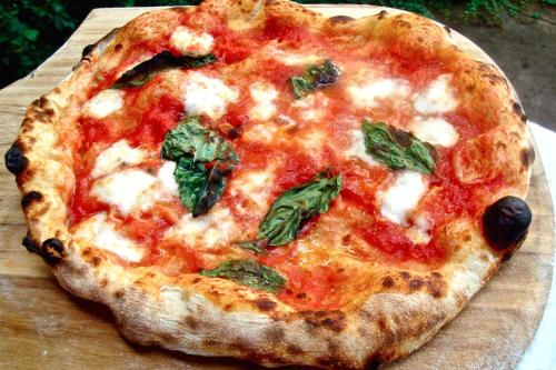 a pizza sitting on top of a wooden cutting board at Hotel Ai Sette Nani in Sistiana
