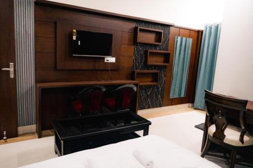 a room with a tv and a bed and chairs at Kesar The Saffron Homestay in Dehradun