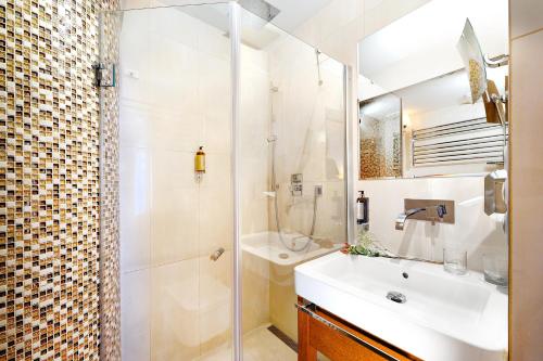 a bathroom with a sink and a shower at Grand Hotel Praha in Tatranská Lomnica