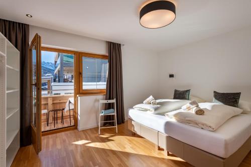a bedroom with a large white bed with a balcony at Chalet Andreashof in Gerlos