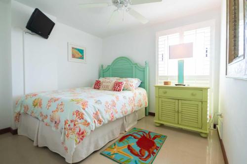 a bedroom with a bed and a dresser and a television at Beachfront - Surround View 4BR Penthouse - P516 in Palm-Eagle Beach