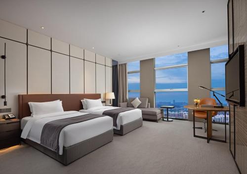 um quarto de hotel com duas camas e uma televisão em Wanda Yi Hotel Chengdu em Chengdu