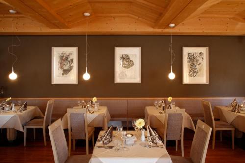 une salle à manger avec des tables, des chaises et des lumières dans l'établissement Hotel Am Reschensee, à Resia