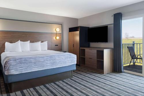 a hotel room with a bed and a flat screen tv at AmericInn by Wyndham Beaver Dam in Beaver Dam