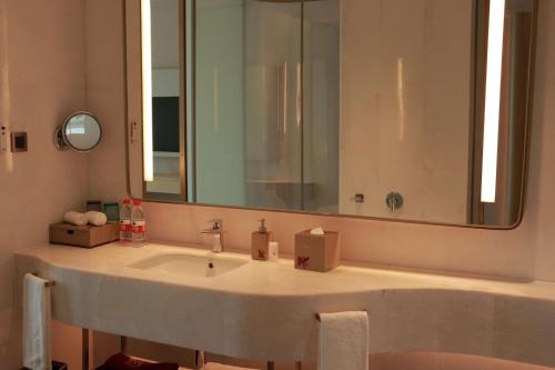 a bathroom with a sink and a large mirror at Wyndham Garden Jinjiang in Jinjiang