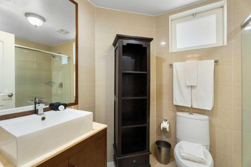 Un baño con lavabo, inodoro y espejo. en Beachfront - Absolute Luxury 2BR condo - BC254, en Palm-Eagle Beach