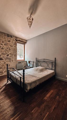 une chambre avec un lit et un mur en pierre dans l'établissement Gîte le relais de la diligence, à Saint-Lazare
