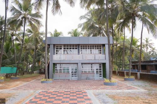 a building with palm trees in front of it at Reunion Ocean Waves - Beach House in Udupi