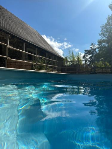 une piscine d'eau en face d'un bâtiment dans l'établissement Gîte le relais de la diligence, à Saint-Lazare