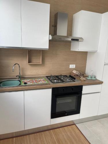 eine Küche mit weißen Schränken und einem Herd mit Backofen in der Unterkunft Nina rooms&apartments in Lizzano