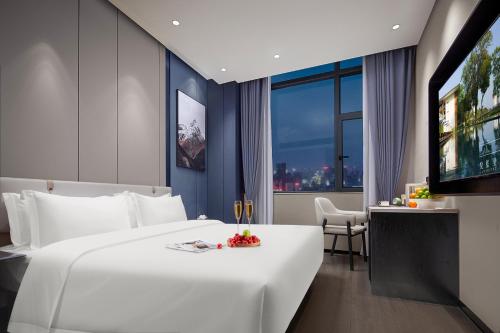 a hotel room with a large white bed and a television at 悦蓝里s酒店成都春熙路宽窄巷子店 in Chengdu