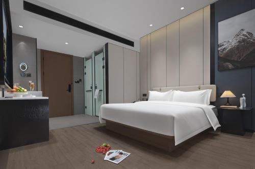 a bedroom with a large white bed and a bathroom at 悦蓝里s酒店成都春熙路宽窄巷子店 in Chengdu