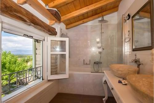 a bathroom with a shower and a sink and a window at Siorra Angelina Villa in Perítheia