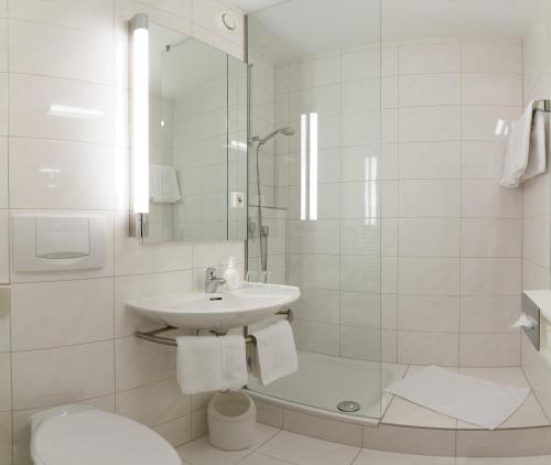 a white bathroom with a sink and a shower at domus Hotel in Munich