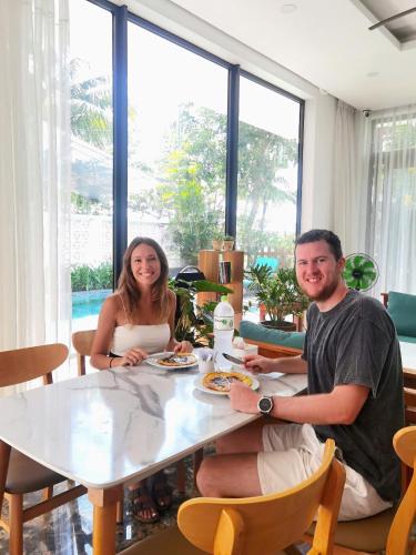 a man and woman sitting at a table with food at Palm Riverside Boutique in Hoi An
