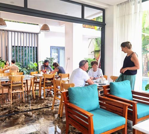 a group of people sitting at tables in a restaurant at Palm Riverside Boutique in Hoi An