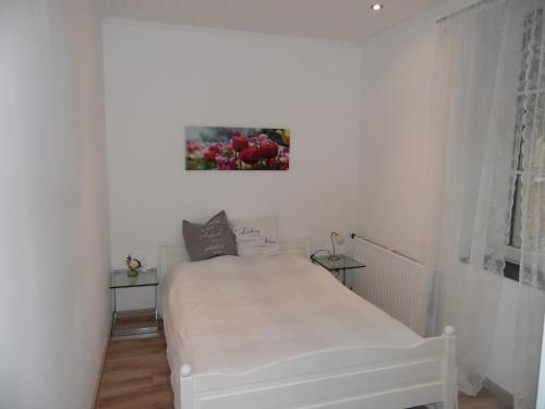 ein weißes Bett in einem Schlafzimmer mit einem Bild an der Wand in der Unterkunft FeWo am Mu-Cafe in Emmerich