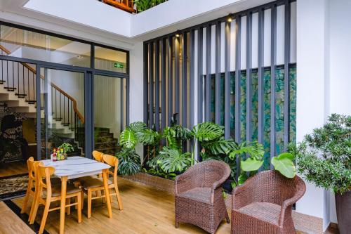 a dining room with a table and chairs and plants at Palm Riverside Boutique in Hoi An