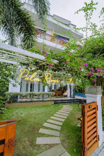 a house with a garden with pink flowers at Palm Riverside Boutique in Hoi An