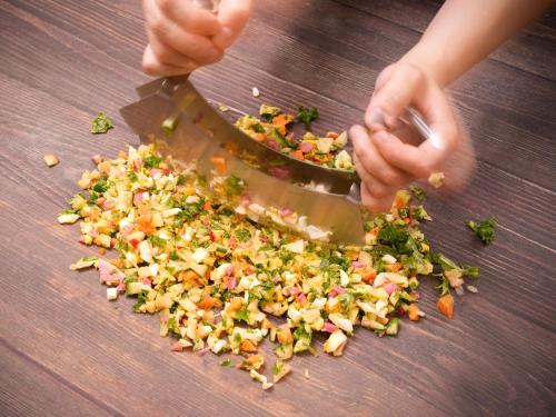 a person cutting up vegetables on a table with a knife at The BREAKFAST HOTEL Fukuoka Tenjin in Fukuoka