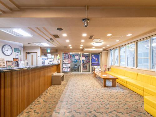 a waiting area of a store with a yellow couch at Tabist Arc Inn Matsumi in Beppu