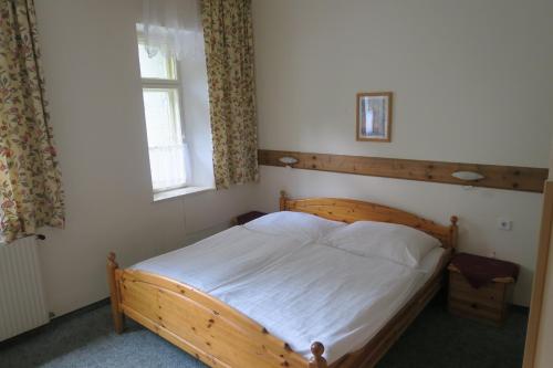 a bedroom with a wooden bed and a window at Pension am Lackenbach in Langau