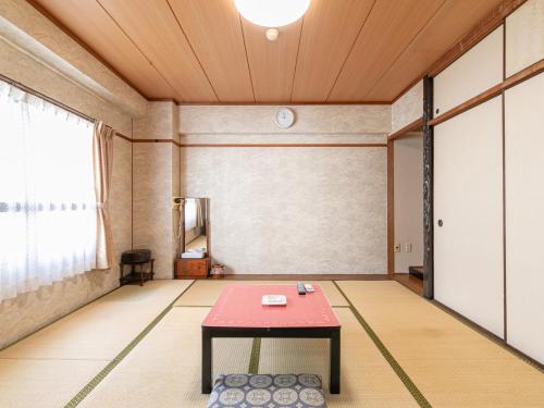 a room with a red table in the middle of it at Tabist Arc Inn Matsumi in Beppu