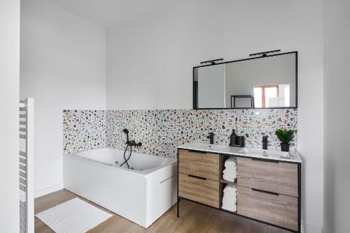une salle de bain avec une baignoire, un lavabo et un miroir dans l'établissement Charmante Maison - Le Cœur des Hommes - Wifi, Balnéo, Hammam, à Beaupréau