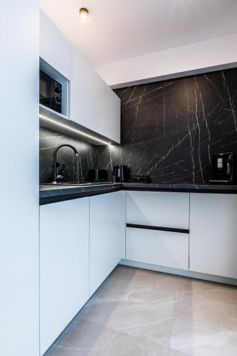 a kitchen with white cabinets and a black counter top at Apartamenty Krokusowa Dolina in Kościelisko