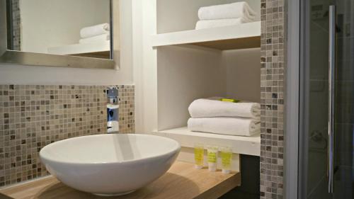 La salle de bains est pourvue d'un lavabo blanc et de serviettes. dans l'établissement Little Suite - Héloise, à Lille