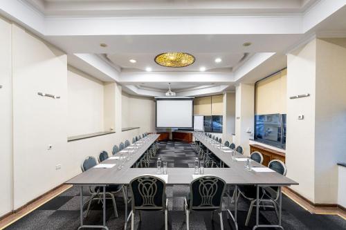 a conference room with tables and chairs and a projector screen at Crystal Palace Hotel in Bucharest