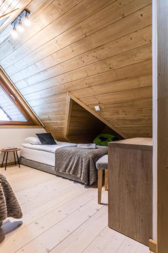 a bed in a room with a wooden ceiling at Apartamenty Krokusowa Dolina in Kościelisko