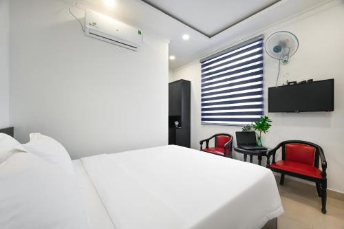 a white bedroom with a bed and two red chairs at Trung Mai Hotel - Nguyễn Thái Bình in Ho Chi Minh City