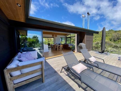 a house with a bed and chairs on a deck at Nestled in Nature, 2 Bedroom Treetop Home in Raglan