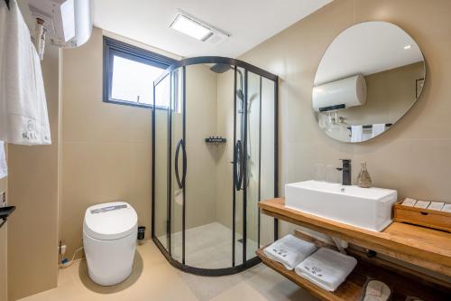 a bathroom with a shower and a toilet and a sink at Xizhou Feng Shangju in Dali