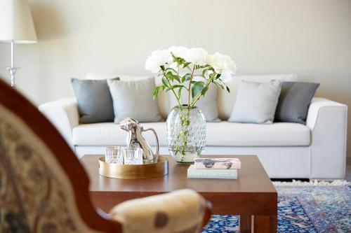 a living room with a vase of flowers on a coffee table at Mon Repos Palace - Adults Only in Corfu
