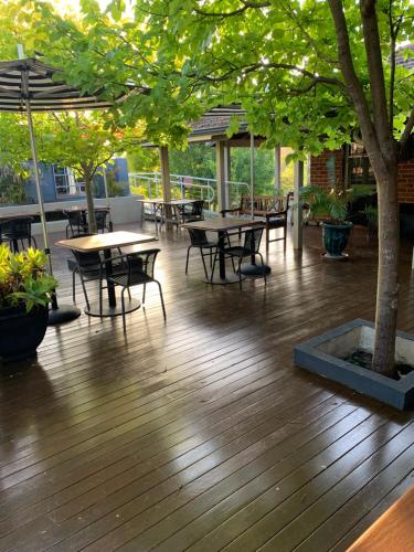 Una terraza con mesas y sillas y un árbol. en Bridgetown Valley Lodge, en Bridgetown