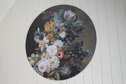 a painting of a vase of flowers on a wall at Ithaka Beach House, unieke plek met vrij parkeren! in Noordwijk