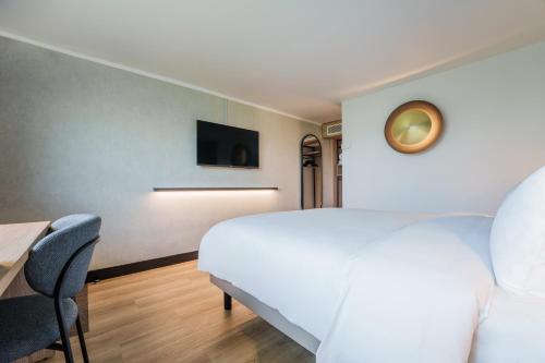 a bedroom with a bed and a desk and a tv at Campanile PRIME - Nice Airport in Nice